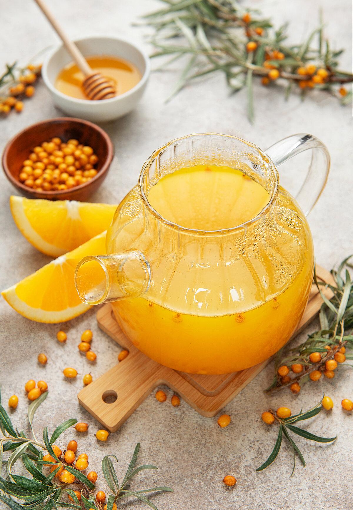 Heißes Wasser wird über Beeren und Zitrusfruchtscheiben in eine Glastasse gegossen.